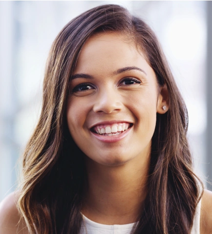 Young woman smiling at camera in bright indoor setting for dental care website.