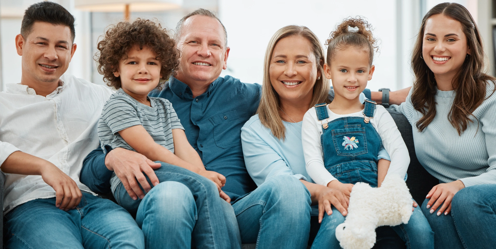 Happy multi-generational family smiling together in casual clothing at dental office.