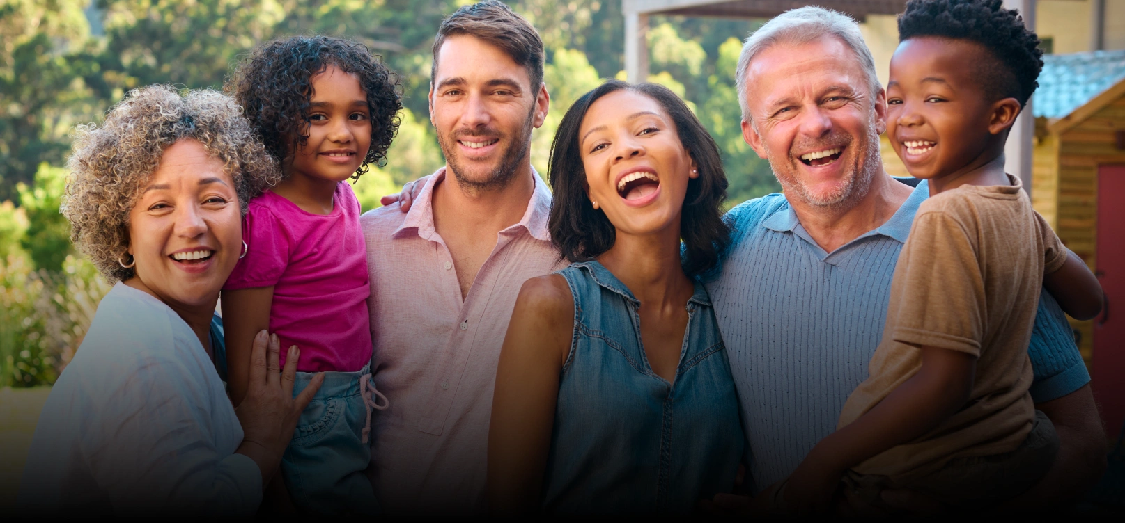 Diverse group of smiling patients and staff posing together outdoors at Dr. Bob's Dental Care.