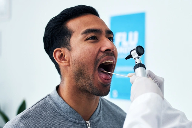 Man receiving dental examination from dentist in clinical setting with blue background