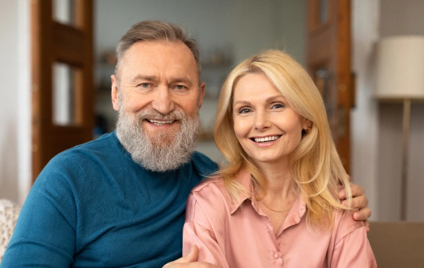 Two smiling adults posing together in a bright, modern dental office setting.
