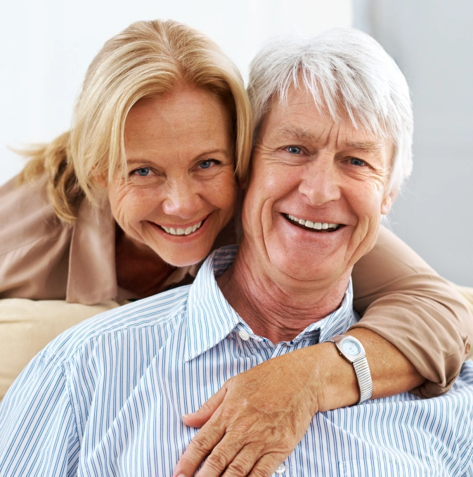 Smiling mature couple posing together in casual embrace indoors