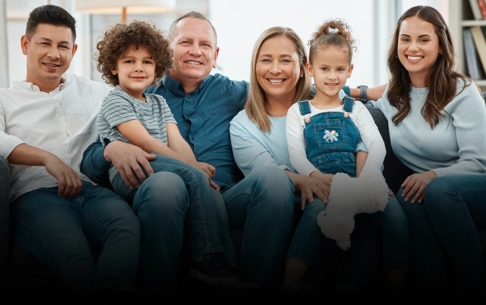 Multi-generational family smiling together in dental office wearing matching teal shirts