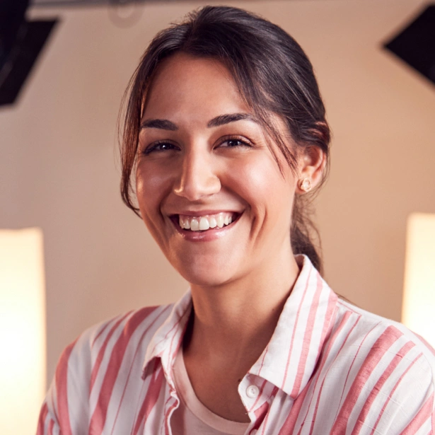 Smiling woman in pink striped shirt at dental office reception area
