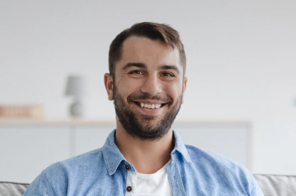Smiling man in blue shirt sitting indoors at dental office setting