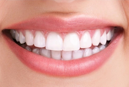 Close-up of a bright, healthy smile showing white teeth and pink lips against skin tone.